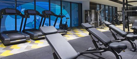 A gym with exercise equipment, including treadmills and weight machines, and benches.