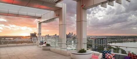 A modern rooftop terrace with a city view, large potted plants, and a seating area.