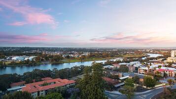 A panoramic view of a town with a river, buildings, and a park.