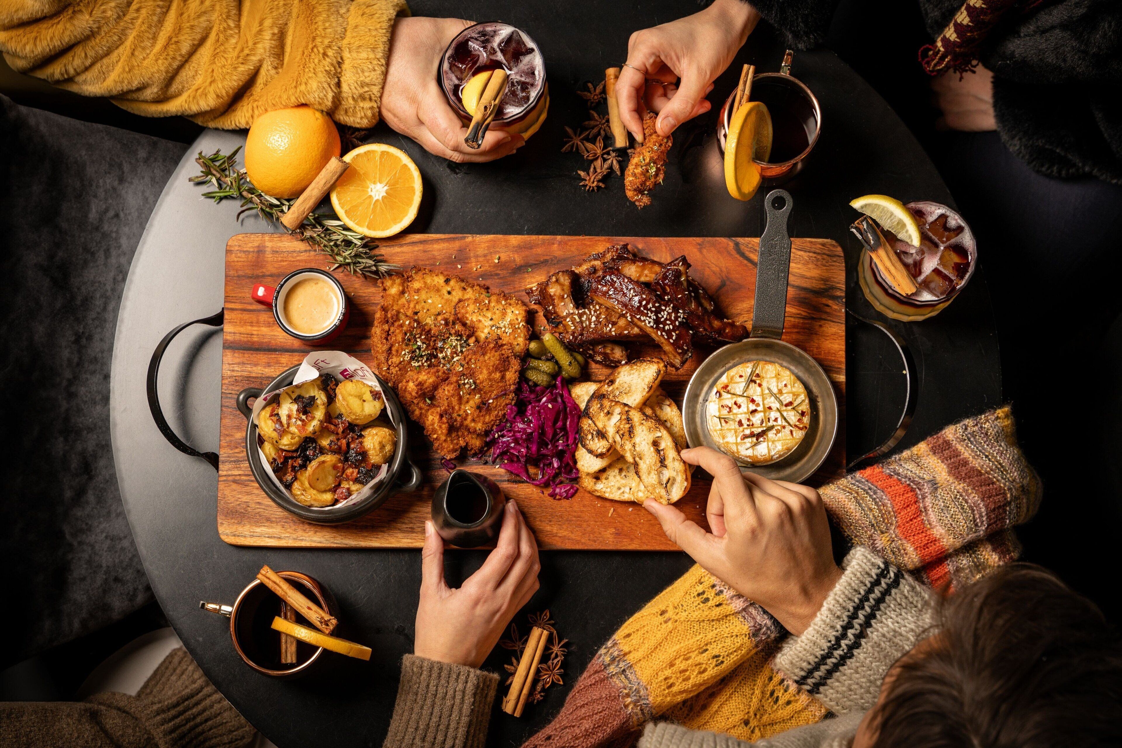 A round table with a variety of dishes, drinks, and garnishes.