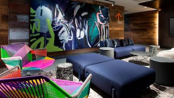 Ein moderner Lounge-Bereich mit bunten Sesseln, einem großen abstrakten Gemälde und einer blauen Sofagarnitur.
