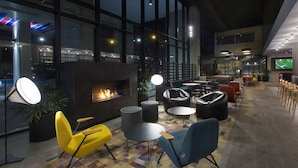 A modern lounge area with a fireplace, seating, and a large TV screen. - Aloft by Marriott Perth (Rivervale)