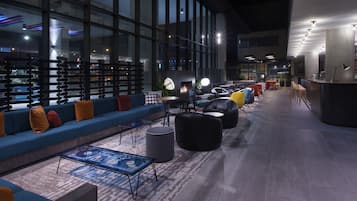 Un espacio lounge moderno con un sofá grande, diversas opciones de asientos, una barra de café y una chimenea.