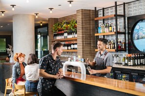 A bar area with a counter, shelves with bottles, and a large window.