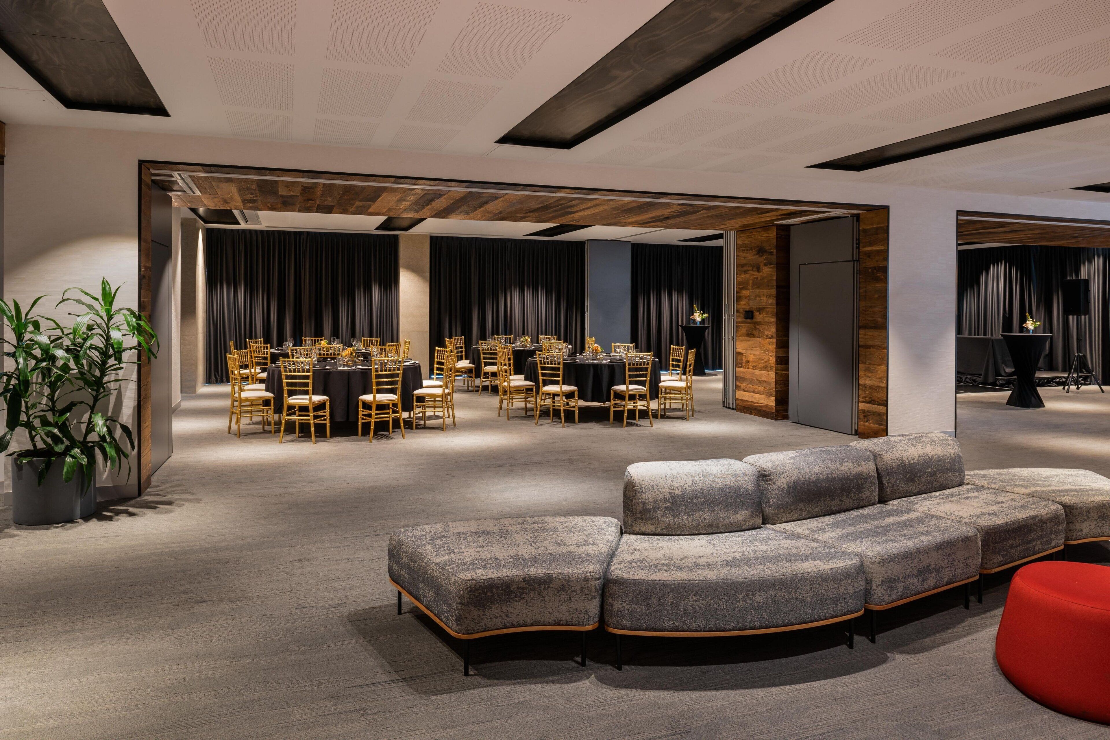 A modern conference room with a long table and chairs, a grey sofa, and a red accent chair.
