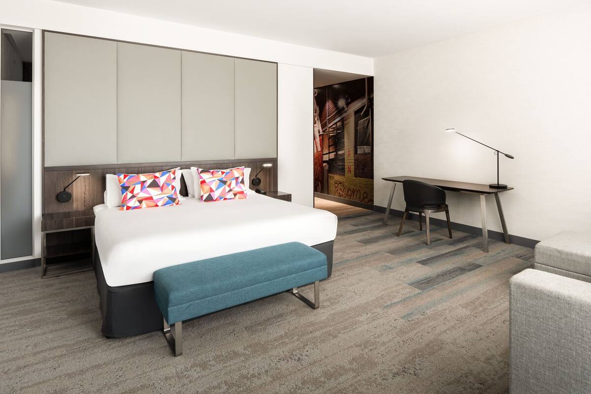 Et moderne hotelværelse med en stor seng, et skrivebord og en stol.