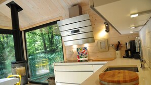 A modern kitchen with a large window, a stove, and a dining area with a yellow chair. - Chalet in Oignies near French Border (Oignies en Thierache)