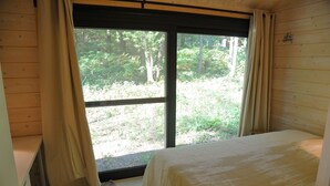 A bedroom with a large window, a bed, and a wooden wall. - Chalet in Oignies near French Border (Oignies en Thierache)