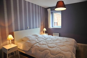 Cozy retreat with a large bed, bedside tables, and a window with a white curtain.