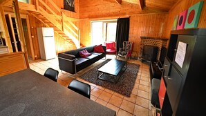 Een knus chalet met een houten interieur, een open haard, een bank en een eethoek.