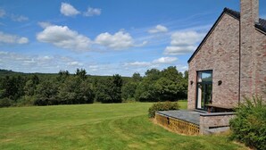 A brick house with a large lawn and a wooden deck.
