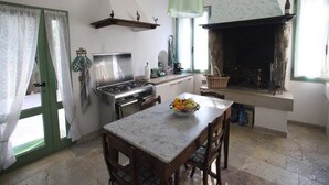 Une cuisine équipée d’une cuisinière, d’une table à manger avec des chaises, d’une horloge et d’une cheminée.