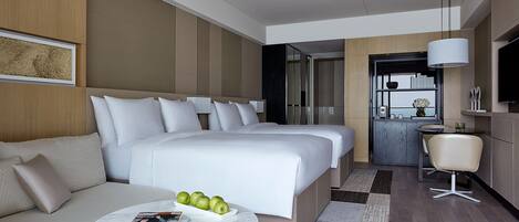 A hotel room with a large bed, a sofa, a dining area, and a TV.