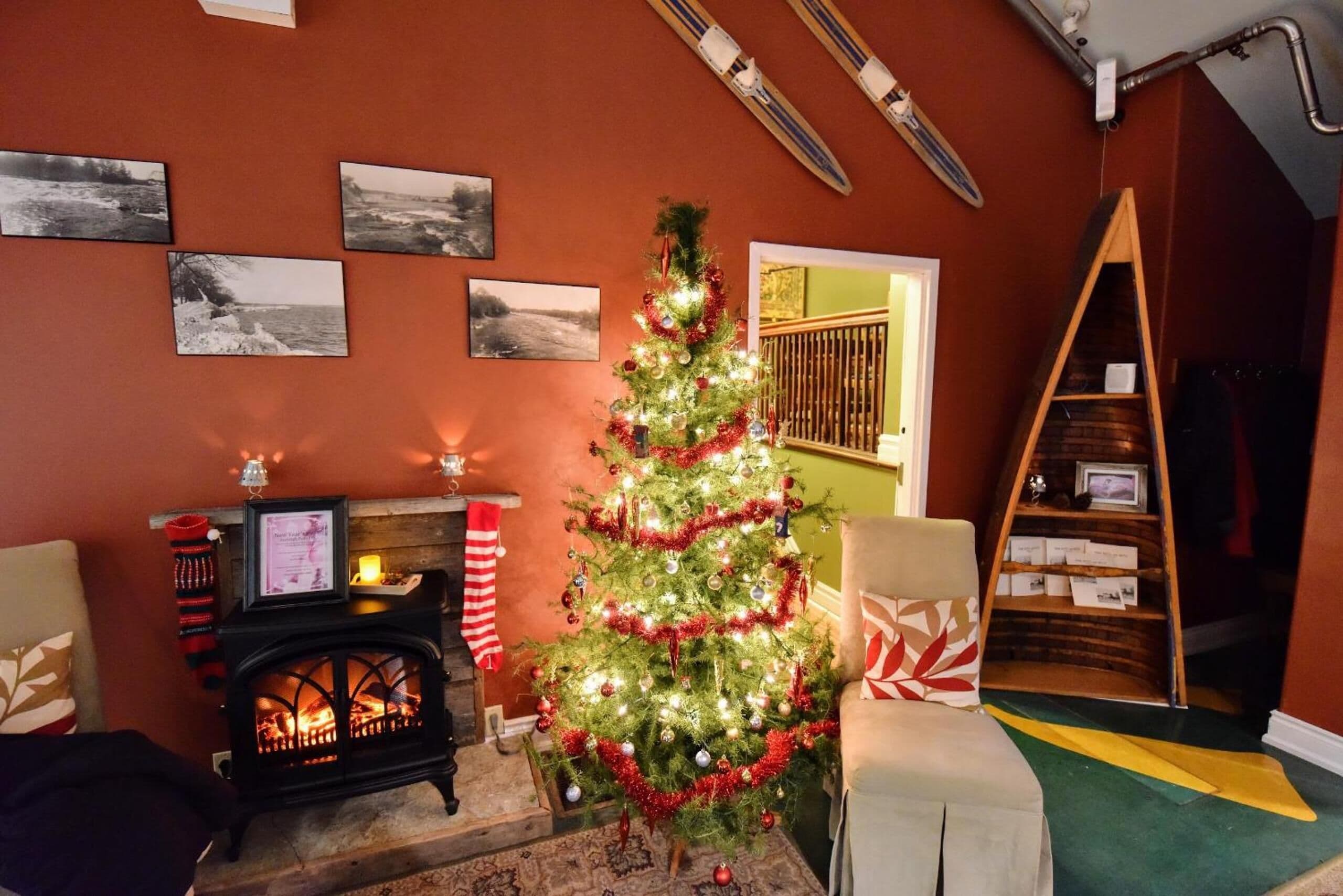 Un salon chaleureux avec une cheminée, un sapin de Noël décoré et une bibliothèque.