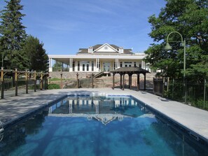 A swimming pool with a gazebo and a large house in the background.