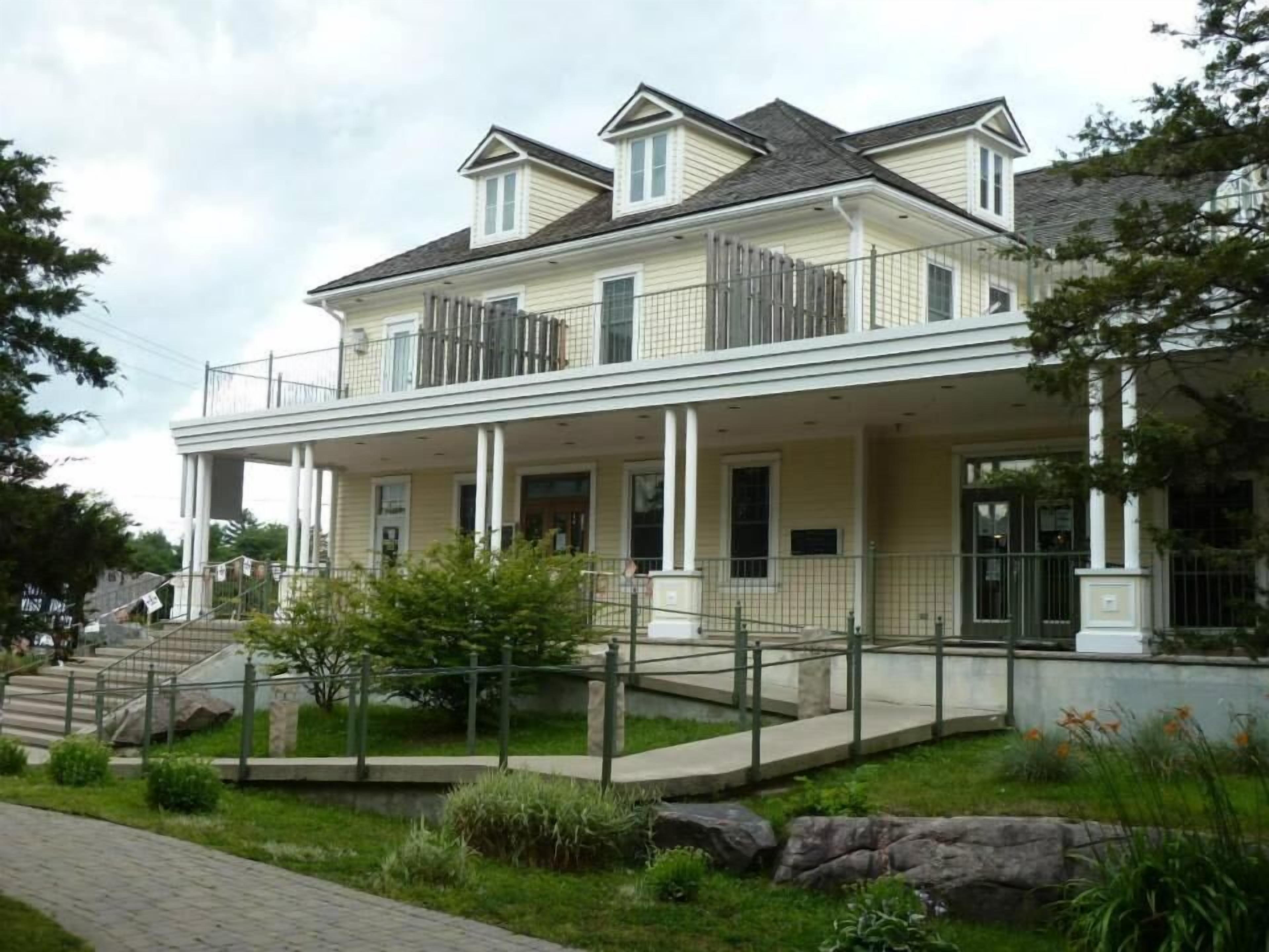 A two-story building with a balcony, a covered porch, and a staircase leading to the entrance.