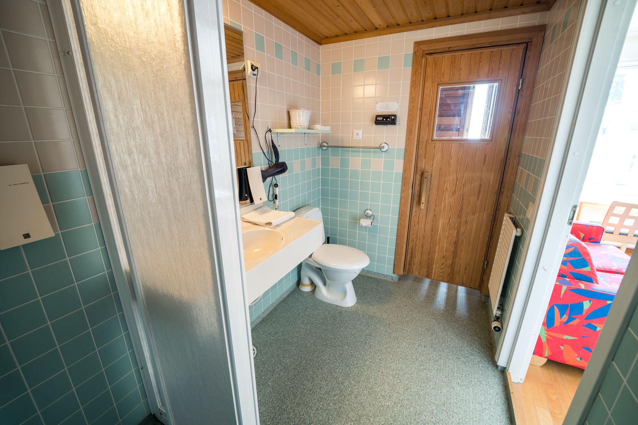 Une salle de bain avec des toilettes, un lavabo et une porte en bois.