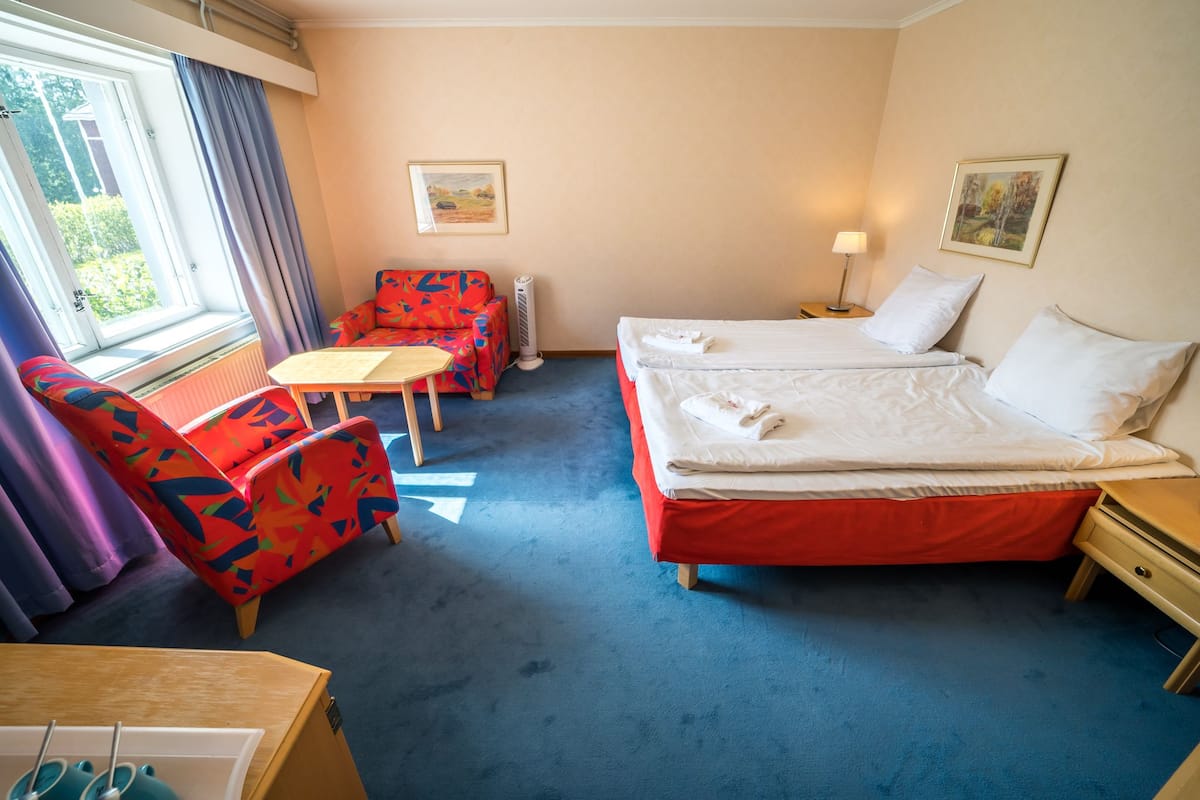 Een hotelkamer met een bed, een stoel, een tafel en een raam met gordijnen.