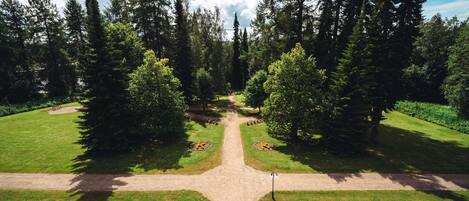 Um parque com uma trilha central, rodeado por árvores e áreas gramadas.