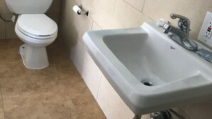 Un baño con inodoro, lavabo y piso de baldosas.