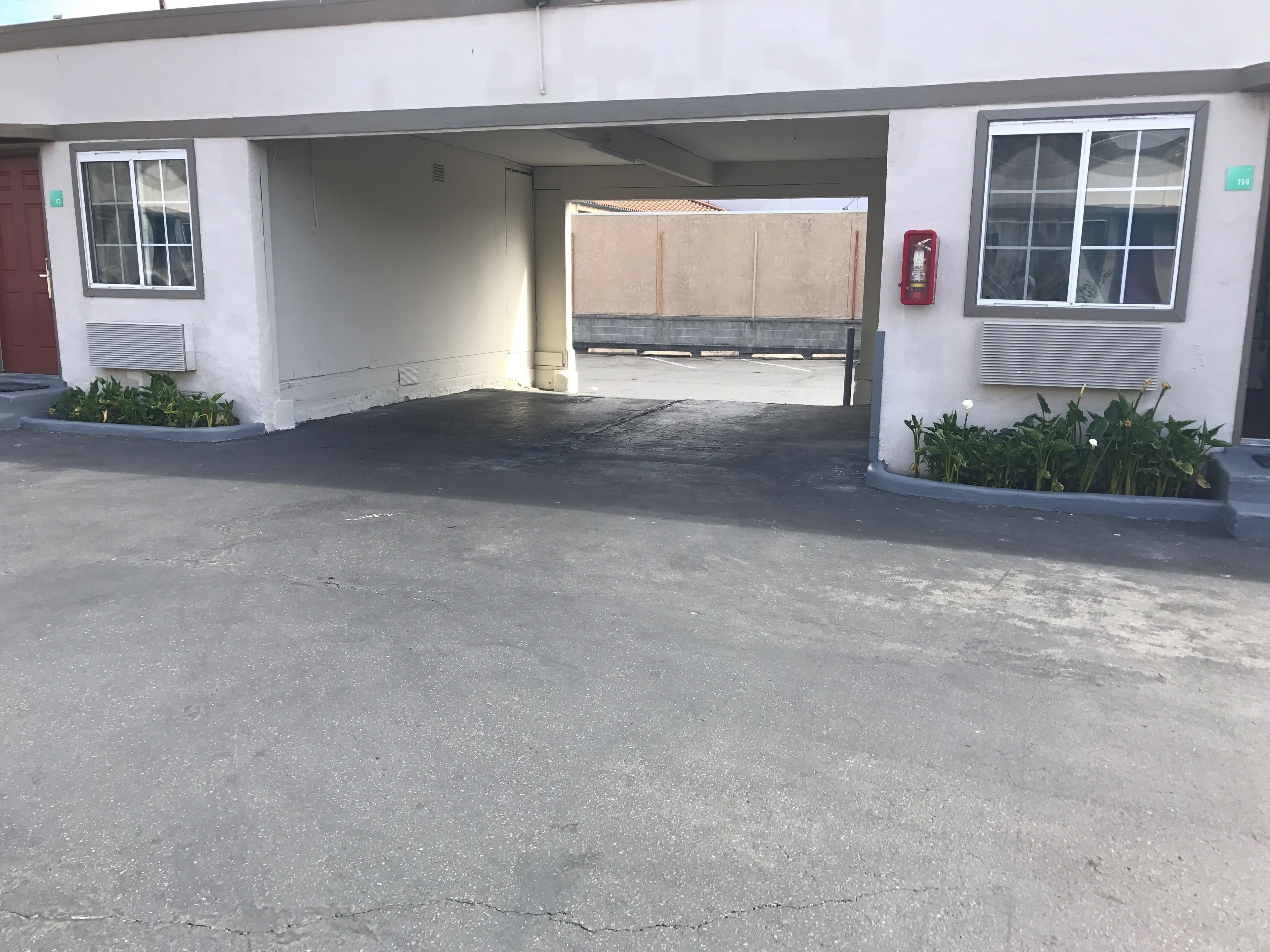 A parking area with a building entrance, a fire extinguisher, and a number sign indicating the location.