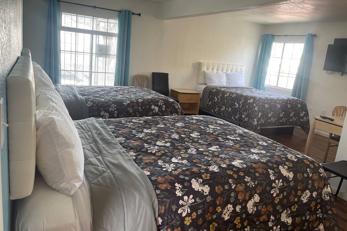 Una habitación de hotel con dos camas, un escritorio pequeño, una silla y un televisor.