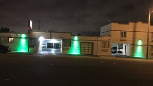 Un área de estacionamiento cerrada con acceso para garaje, un automóvil aparcado a la izquierda y un edificio con puerta de garaje a la derecha.