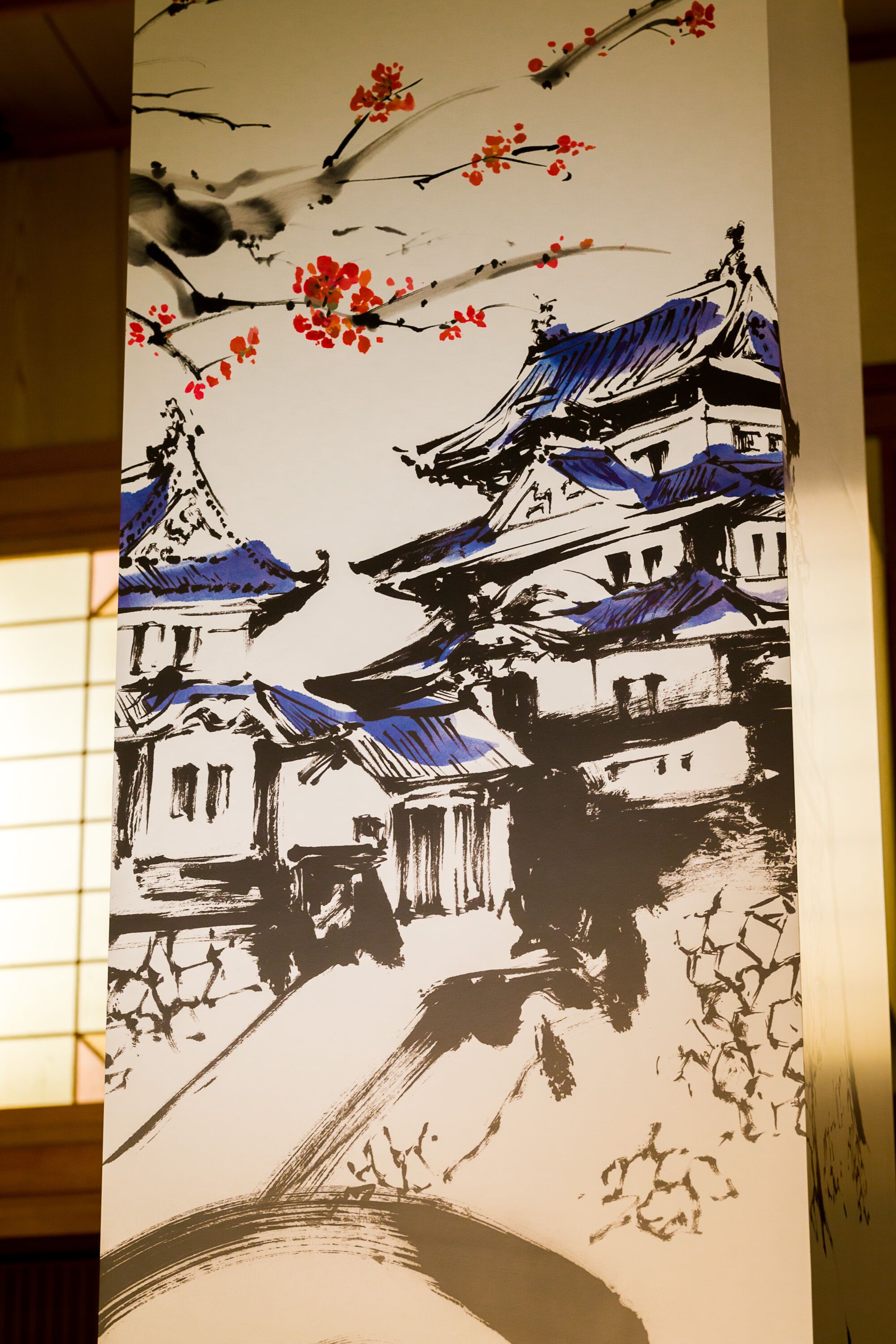 Un edificio japonés tradicional con varios niveles y un techo curvo, rodeado de cerezos en flor.