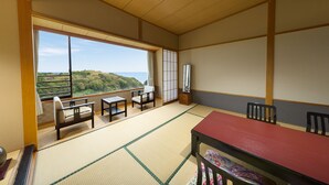 Un salón tradicional de tatami con vistas a un paisaje montañoso.