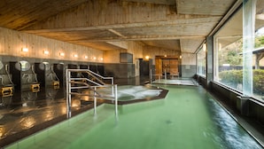 Una sauna con paredes de madera y suelo verde, que cuenta con varios bancos y una escalera central.