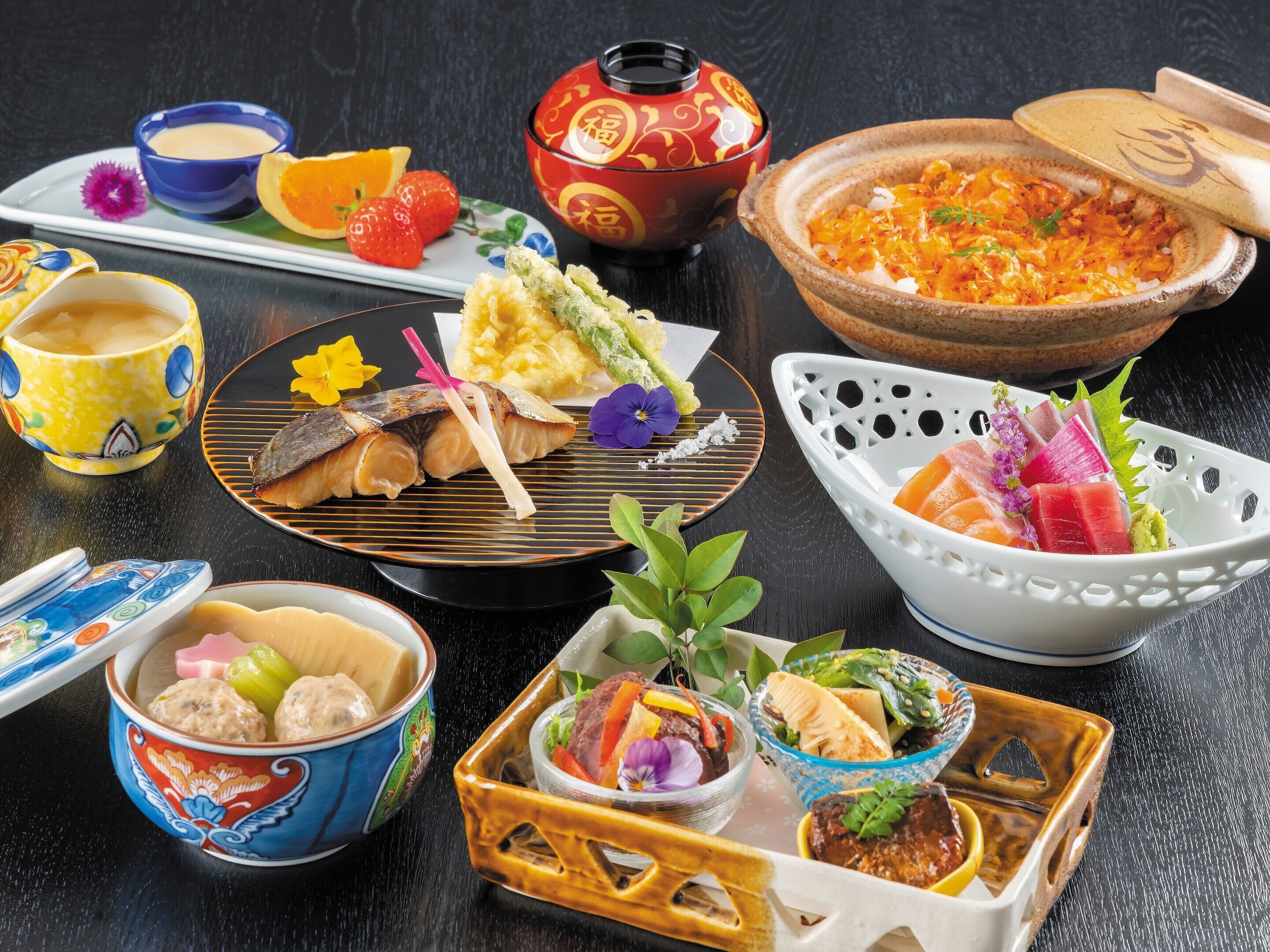 Diverse Japanse gerechten, waaronder sushi, sashimi en andere lekkernijen, gepresenteerd op een tafel met zowel traditioneel als modern servies.