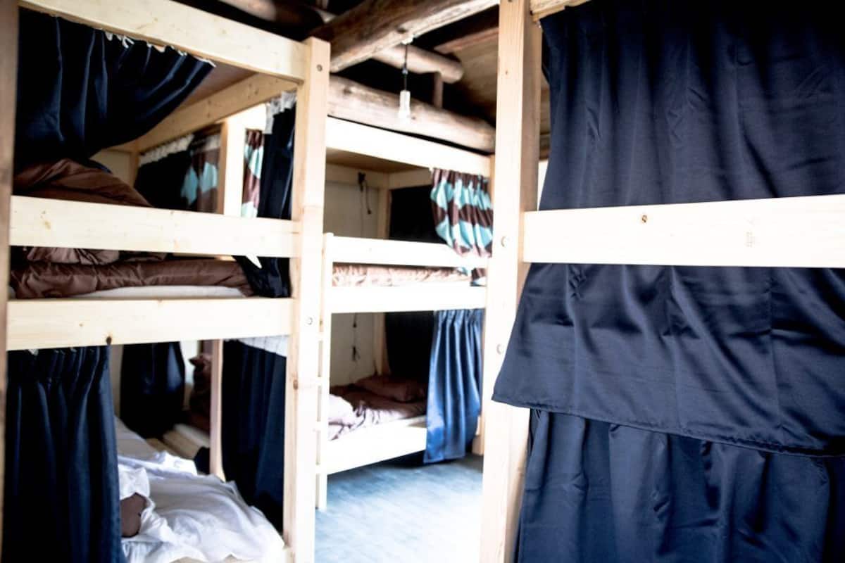 A multi-level bunk bed room with curtains on each bed.