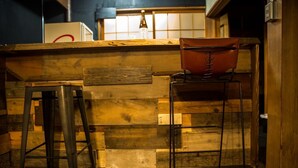 Un rústico área de bar con paneles de madera, un taburete metálico y un sillón de cuero.