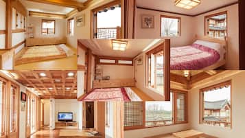A traditional Japanese-style room with tatami flooring, a low wooden bed, a television, and a view of a traditional building outside.