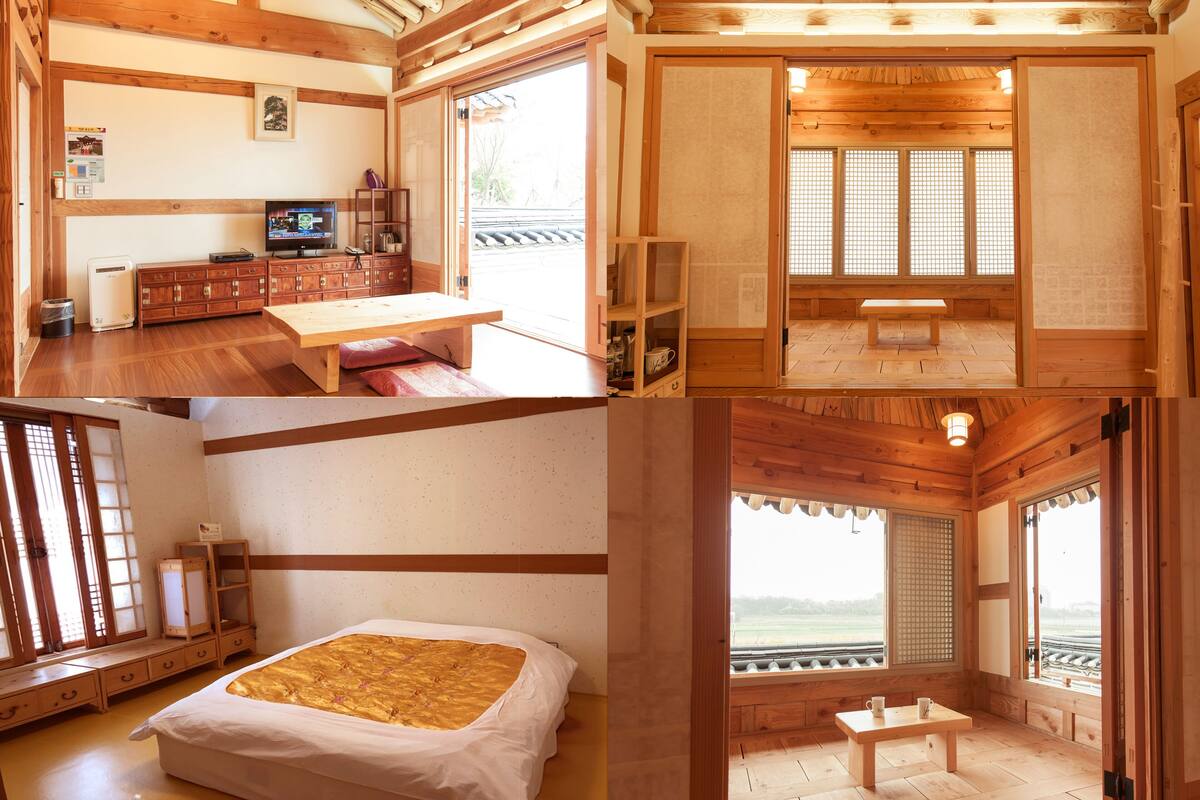 A traditional Japanese-style room with tatami flooring, a low wooden bed, a wooden desk, and a sliding door with a view of the outdoors.