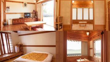 Una habitación tradicional japonesa con suelo de tatami, una cama baja de madera, un escritorio de madera y un puertas correderas con vistas al exterior.