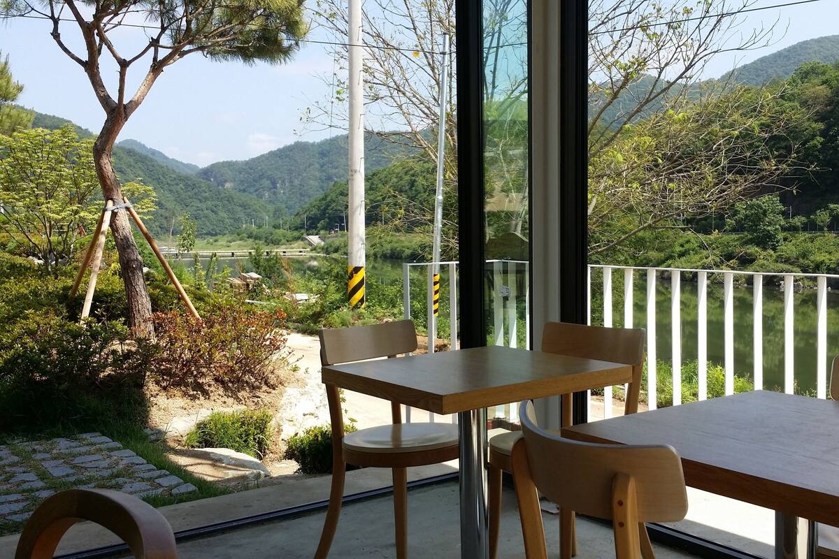 Ein Balkon mit Tisch und Stühlen mit Blick auf eine malerische Fluss- und Berglandschaft.