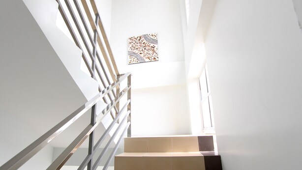 Una escalera moderna con barandilla de metal y un pequeño ventanal con diseño decorativo.