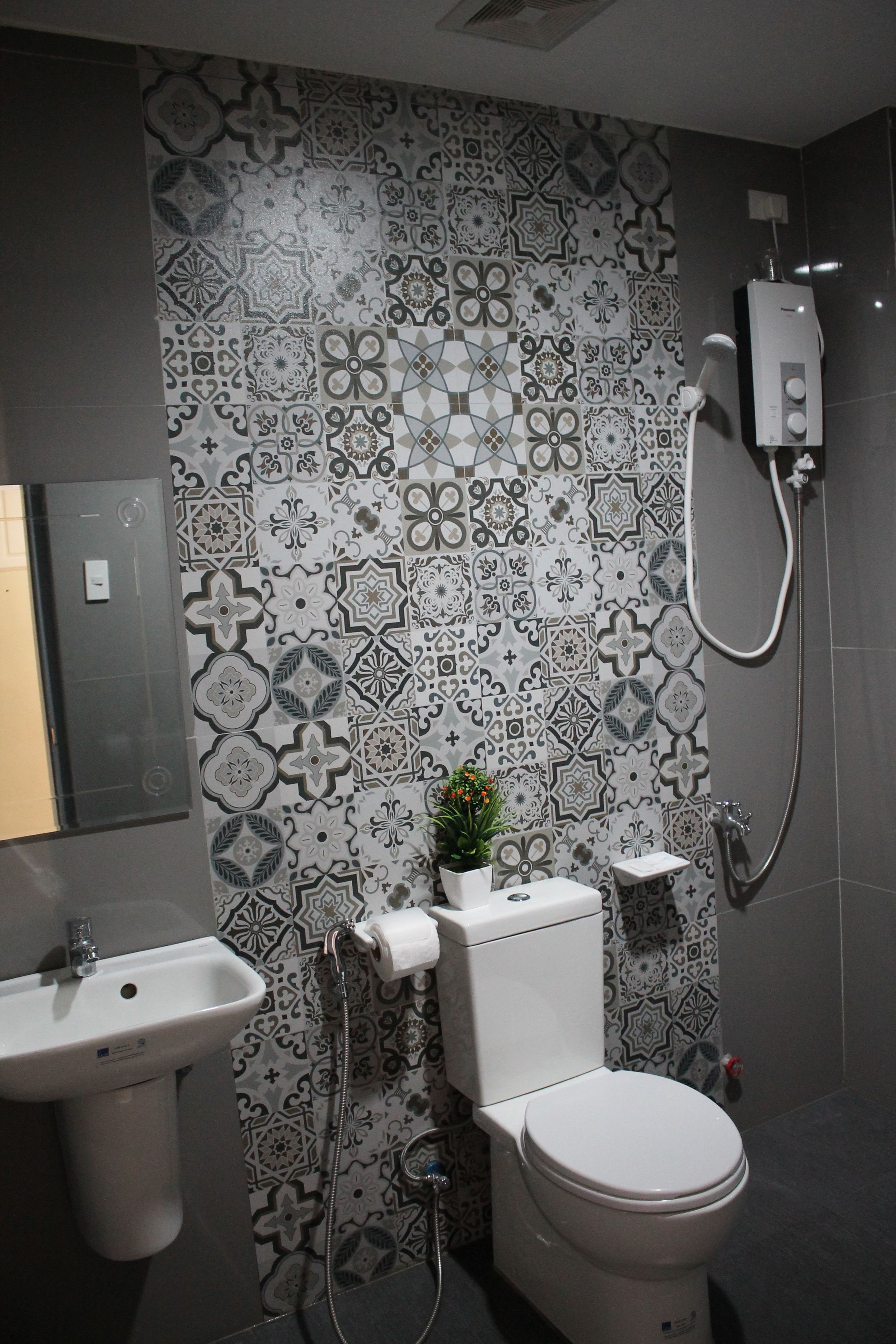 A bathroom with a patterned tile wall, a toilet, a sink, and a shower.