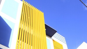 Un edificio moderno con un panel vertical amarillo, ventanas blancas y azules y un techo plano.