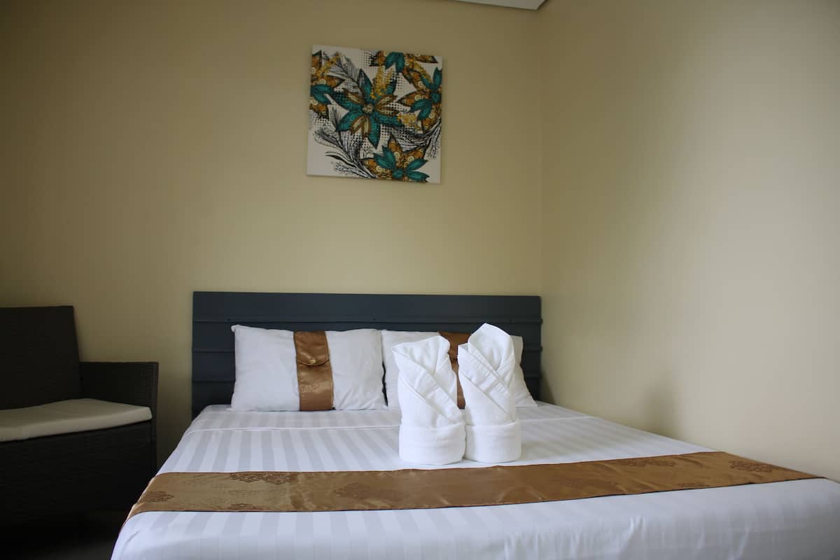 A neatly made bed with white linens and a brown throw, a headboard, and a wall-mounted artwork.