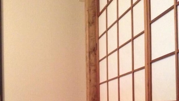 A corner room with wooden flooring, a radiator, and a window with multiple panes. - Condominio Mozu 102 (Sakai)