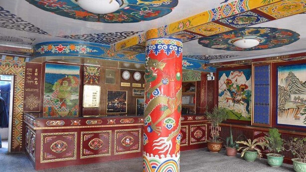 Un interior tradicional con un gran pilar decorativo, una recepción y murales coloridos en paredes y techo.