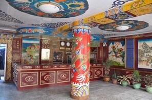 Un interior tradicional con un gran pilar decorativo, una recepción y murales coloridos en paredes y techo.