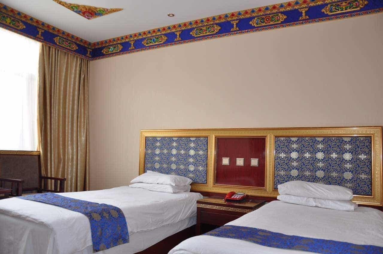 A hotel room with two beds, a wooden nightstand, a red telephone, and a decorative ceiling.
