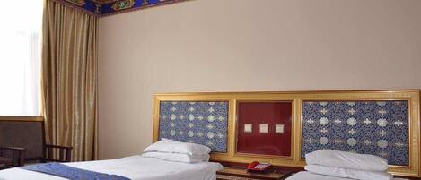 A hotel room with two beds, a wooden nightstand, a red telephone, and a decorative ceiling.