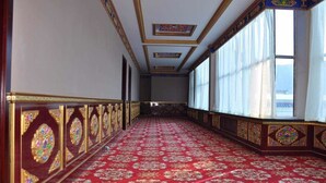 Un largo pasillo con paneles de madera ornamentados y una alfombra roja con estampado.