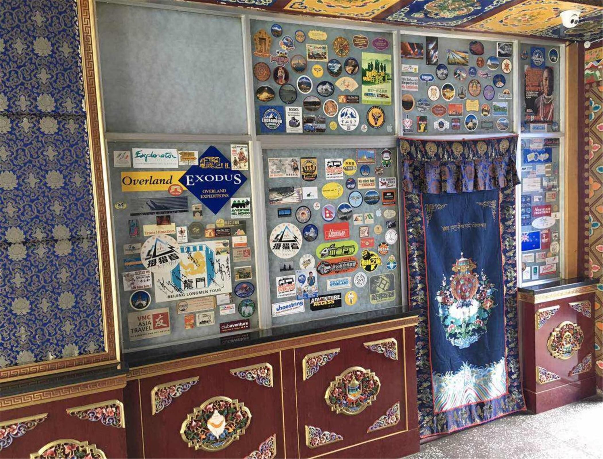 A display case filled with travel-related items and a decorative curtain with intricate designs.