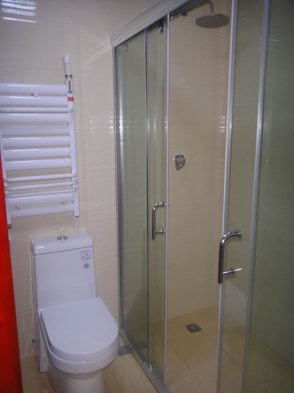 Casa de banho com sanita, cabine de duche e porta-toalhas.