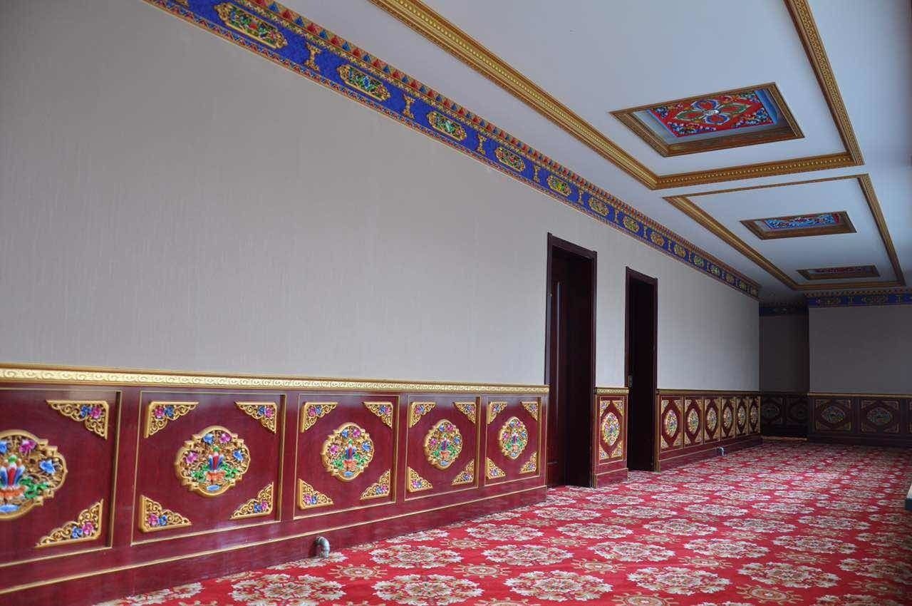 Una habitación con alfombra roja, decoraciones elaboradas en las paredes y un techo con diseños intrincados.